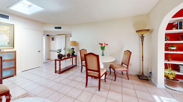 tiled dining room featuring a textured ceiling and a skylight