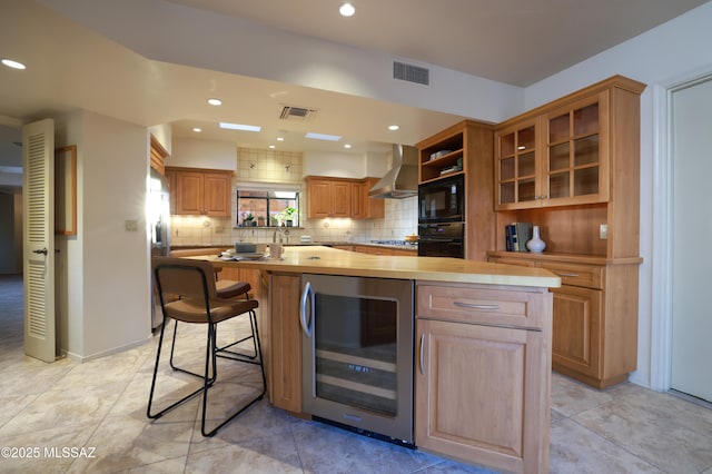 kitchen with beverage cooler, visible vents, black appliances, decorative backsplash, and wall chimney exhaust hood