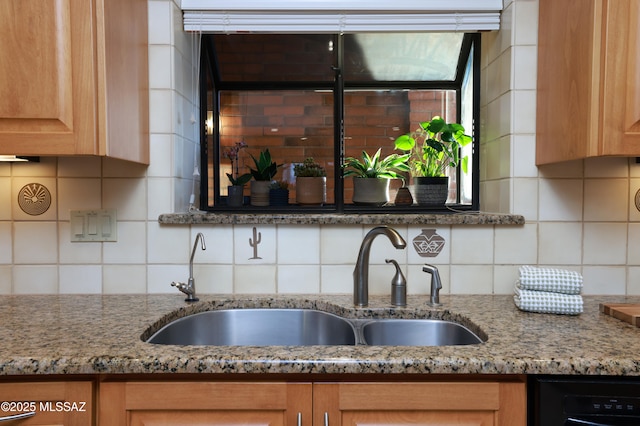 kitchen with black dishwasher, tasteful backsplash, light stone counters, and sink