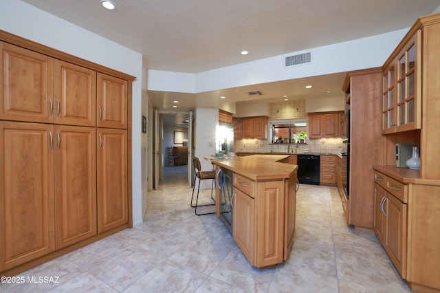 kitchen with visible vents, black dishwasher, light countertops, a center island, and glass insert cabinets