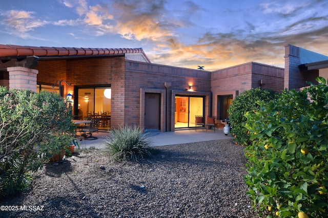 back house at dusk featuring a patio area