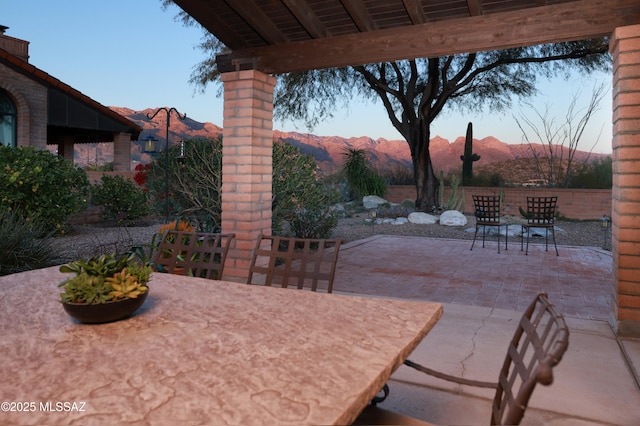 view of patio featuring outdoor dining area, a mountain view, and fence