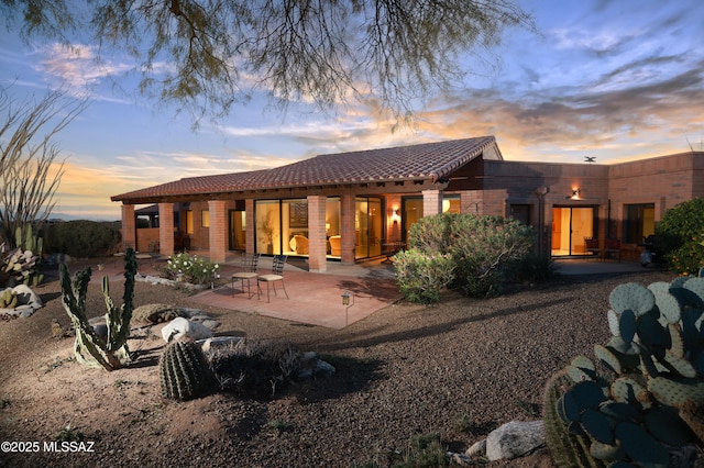 back house at dusk with a patio