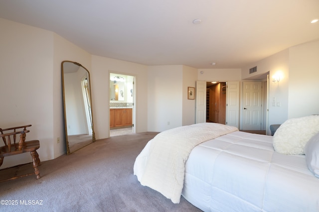 bedroom featuring light colored carpet and ensuite bath