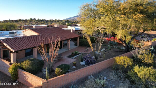 pueblo-style house featuring a garage, concrete driveway, and brick siding