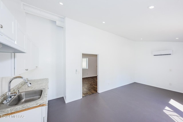 kitchen featuring sink, an AC wall unit, and white cabinets