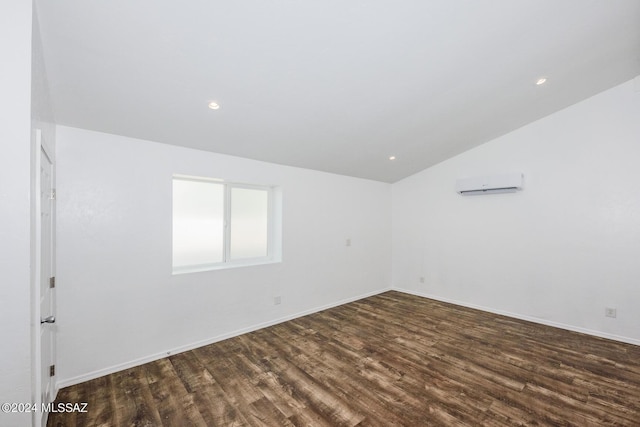 unfurnished room with a wall unit AC, vaulted ceiling, and dark hardwood / wood-style floors