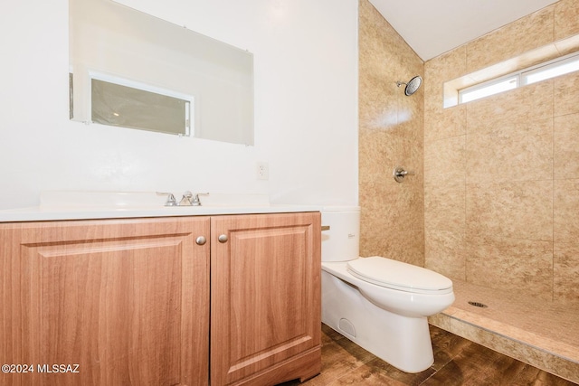 bathroom with tiled shower, hardwood / wood-style flooring, vanity, and toilet