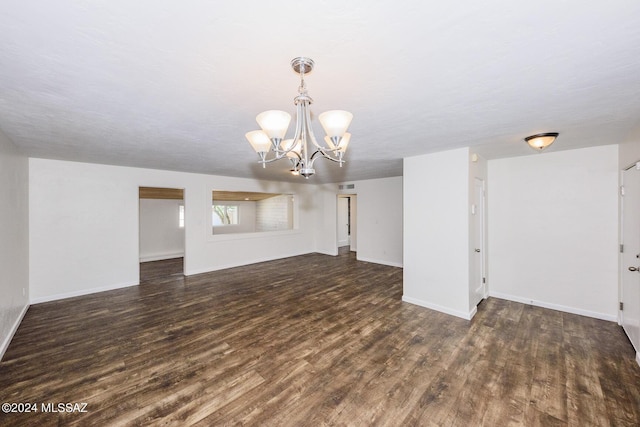 unfurnished living room with dark wood-type flooring and a notable chandelier