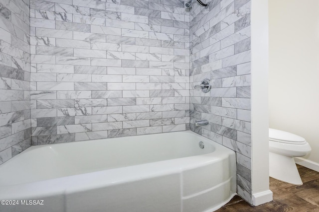 bathroom featuring toilet, hardwood / wood-style flooring, and tiled shower / bath