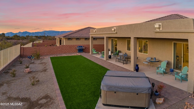 exterior space with a hot tub, a mountain view, and a patio area