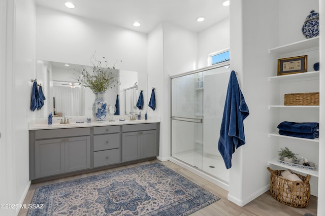 bathroom with hardwood / wood-style flooring, vanity, and a shower with door