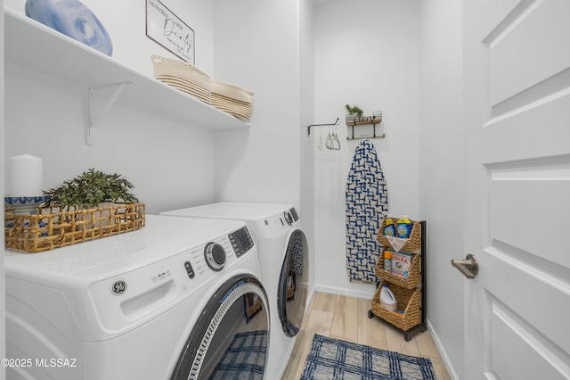 laundry room with washing machine and dryer and light hardwood / wood-style floors