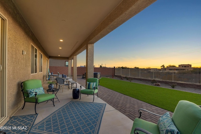 patio terrace at dusk featuring a yard and an outdoor hangout area