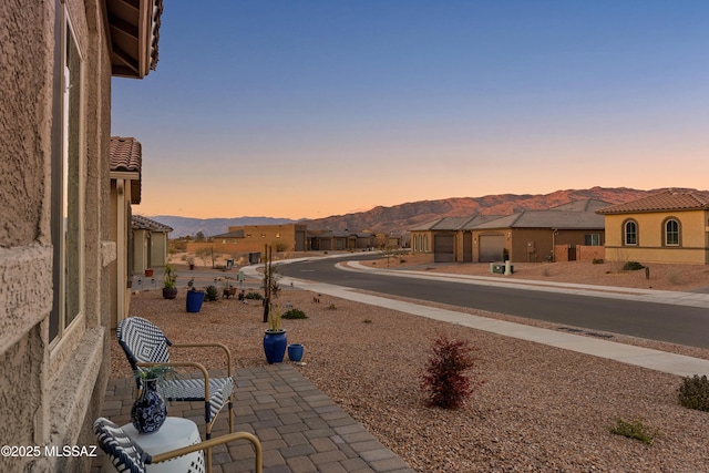 patio terrace at dusk with a garage and a mountain view