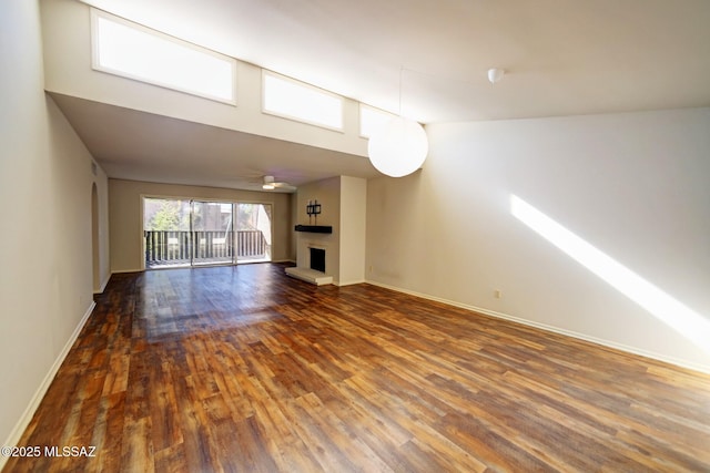 unfurnished living room featuring ceiling fan, dark hardwood / wood-style flooring, and a towering ceiling