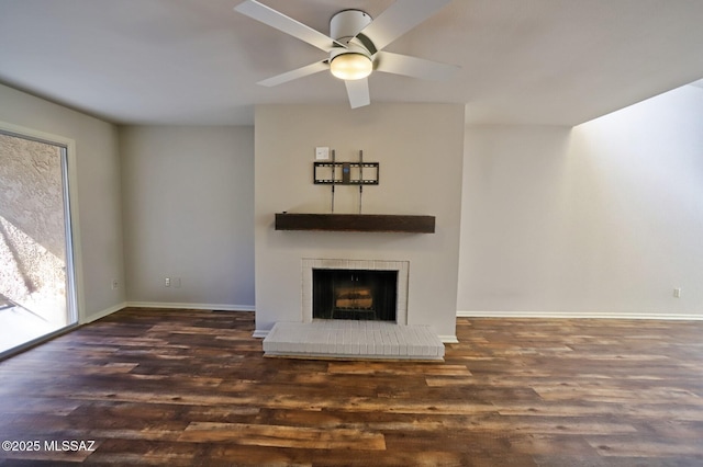 unfurnished living room featuring a brick fireplace, dark wood-type flooring, and ceiling fan