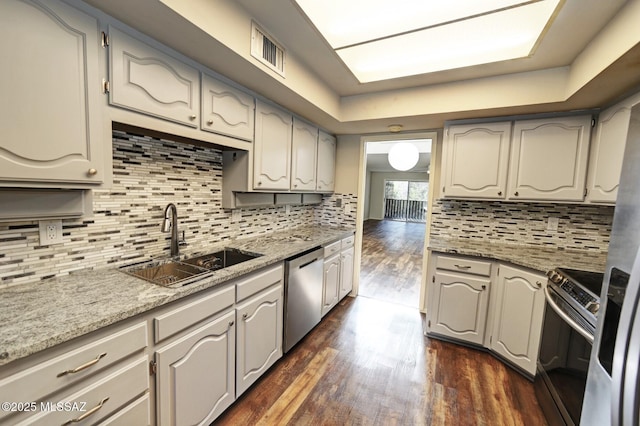 kitchen with stainless steel appliances, light stone countertops, dark wood-type flooring, sink, and backsplash