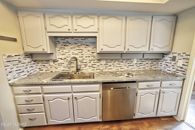 kitchen featuring stainless steel dishwasher, decorative backsplash, sink, and light stone counters