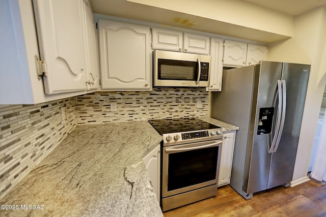 kitchen featuring stainless steel appliances, white cabinets, light stone countertops, decorative backsplash, and dark hardwood / wood-style floors