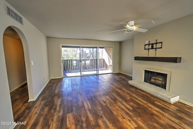 unfurnished living room featuring dark hardwood / wood-style flooring, a brick fireplace, and ceiling fan