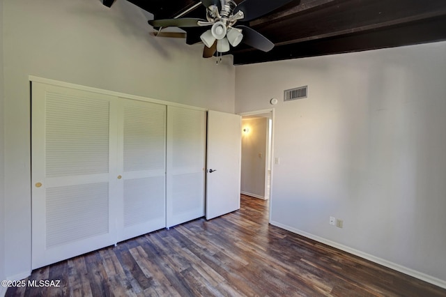 unfurnished bedroom featuring a closet, beamed ceiling, ceiling fan, dark hardwood / wood-style flooring, and high vaulted ceiling