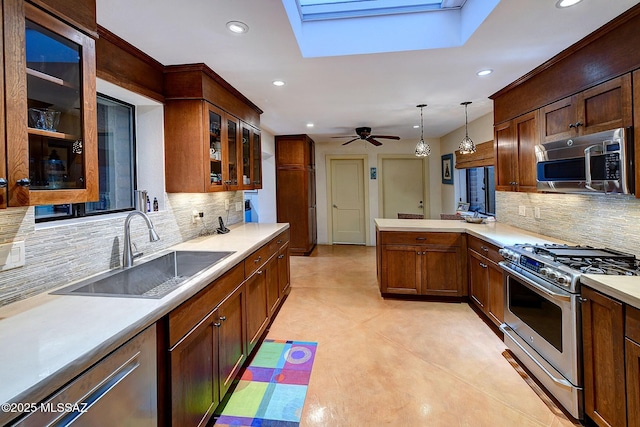 kitchen with pendant lighting, a skylight, sink, ceiling fan, and stainless steel appliances