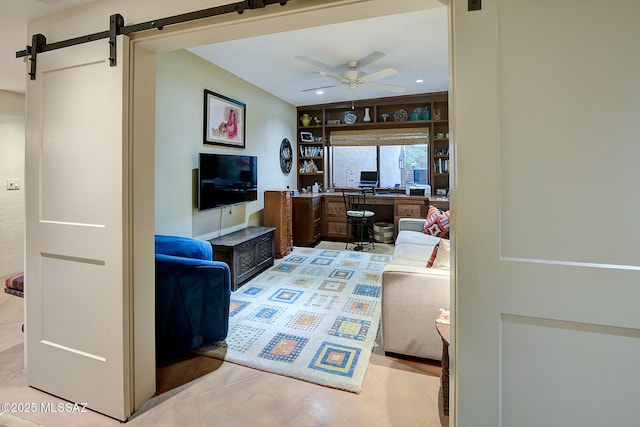 living room with a barn door and ceiling fan