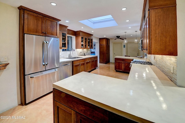 kitchen with pendant lighting, a skylight, sink, kitchen peninsula, and stainless steel appliances