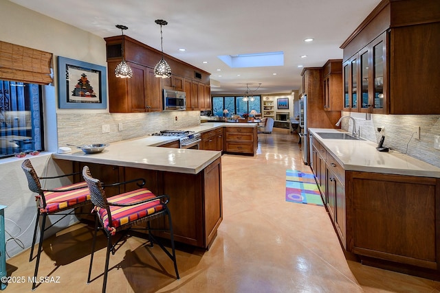 kitchen with pendant lighting, sink, a breakfast bar, premium appliances, and kitchen peninsula