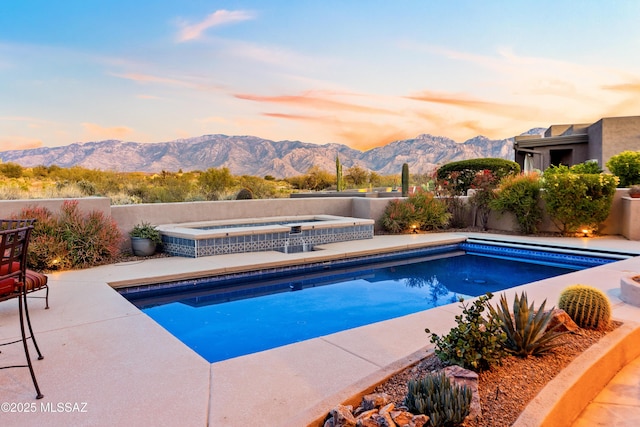 pool at dusk featuring an in ground hot tub and a mountain view