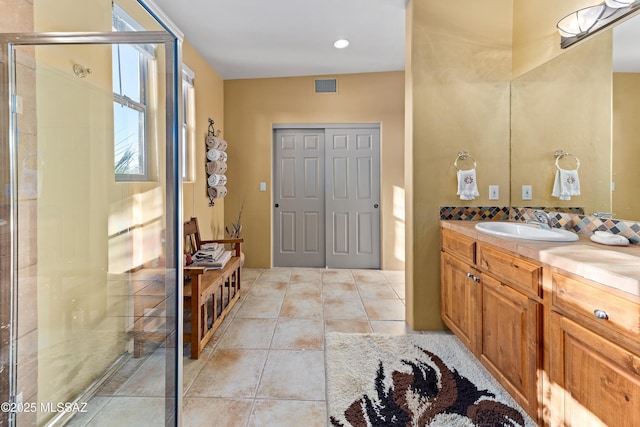 bathroom with a shower with door, tile patterned floors, and vanity