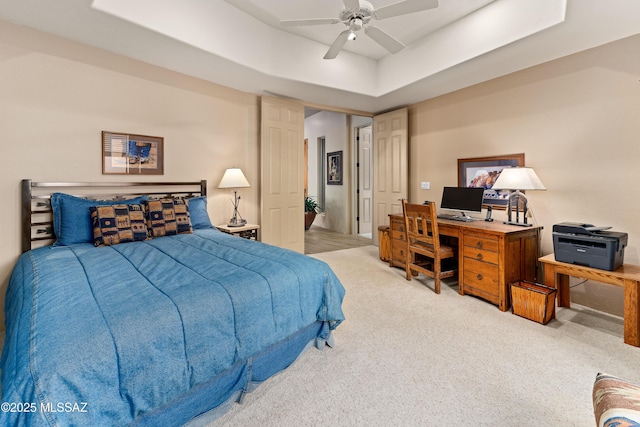 bedroom featuring ceiling fan, light colored carpet, and a raised ceiling