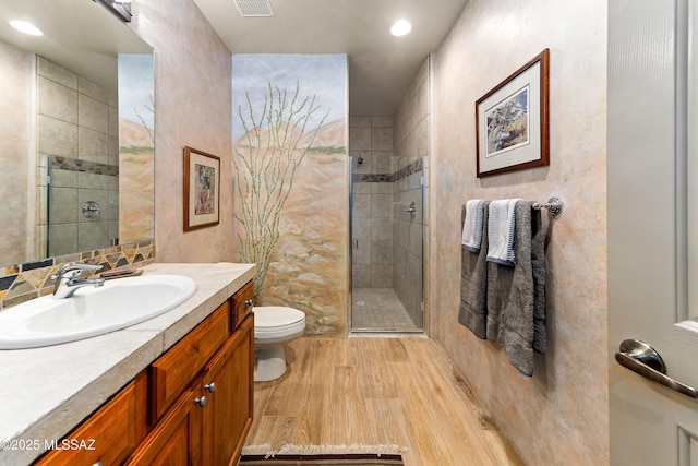 bathroom with toilet, vanity, wood-type flooring, and a shower with door