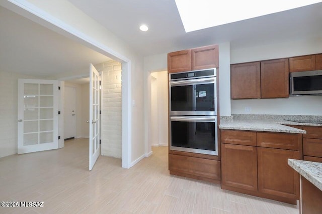 kitchen with light stone countertops, appliances with stainless steel finishes, and french doors