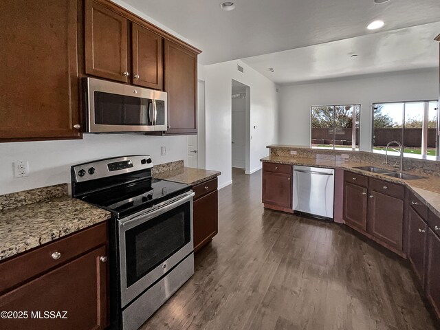 kitchen featuring baseboards, appliances with stainless steel finishes, dark wood-style flooring, and a sink