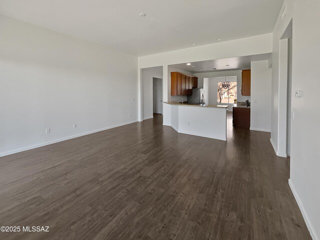 kitchen with recessed lighting, a sink, appliances with stainless steel finishes, light stone countertops, and dark wood-style floors