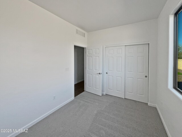 carpeted spare room with visible vents and baseboards