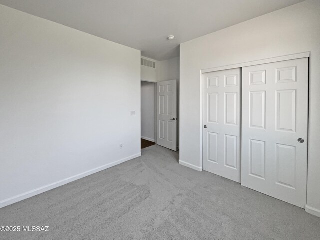 unfurnished room with carpet flooring, visible vents, and baseboards