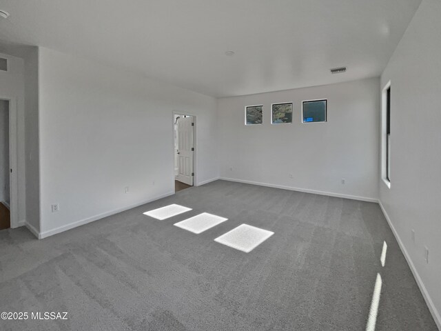 carpeted empty room featuring visible vents and baseboards