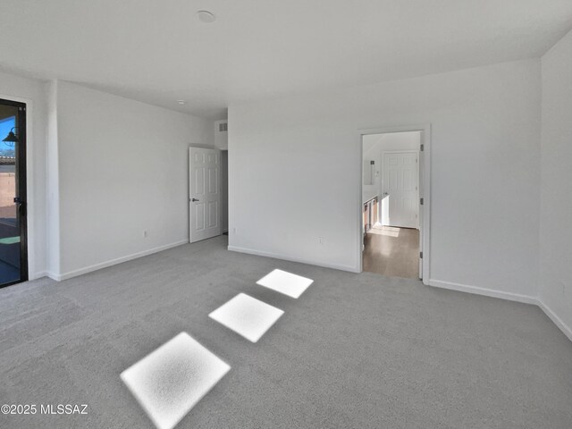 carpeted spare room with visible vents and baseboards