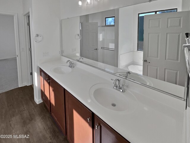 full bath featuring a garden tub, wood finished floors, and a sink