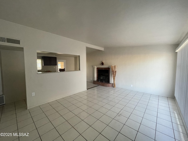 unfurnished living room with light tile patterned flooring and a brick fireplace