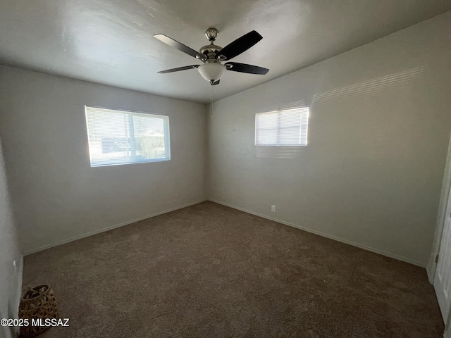 spare room featuring ceiling fan and dark carpet