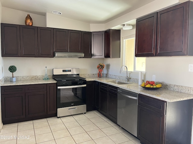 kitchen with light tile patterned flooring, sink, light stone counters, stainless steel appliances, and dark brown cabinets