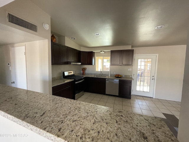 kitchen with appliances with stainless steel finishes, sink, light tile patterned floors, dark brown cabinetry, and kitchen peninsula