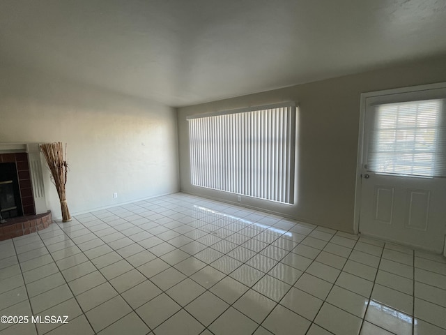 unfurnished living room featuring a tiled fireplace and light tile patterned flooring