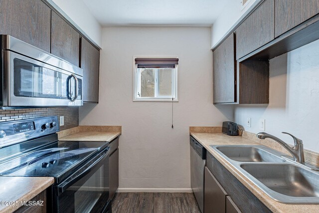 kitchen featuring stainless steel appliances, hardwood / wood-style floors, tasteful backsplash, stacked washer / drying machine, and dark brown cabinets