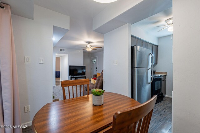 dining space featuring a raised ceiling, ceiling fan, and dark hardwood / wood-style floors