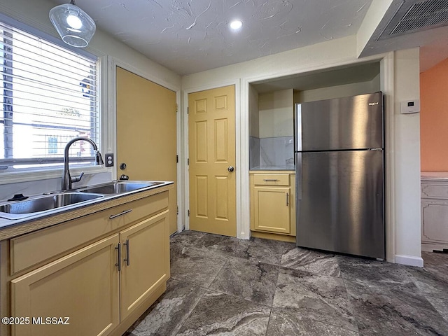 kitchen with a textured ceiling, stainless steel fridge, and sink